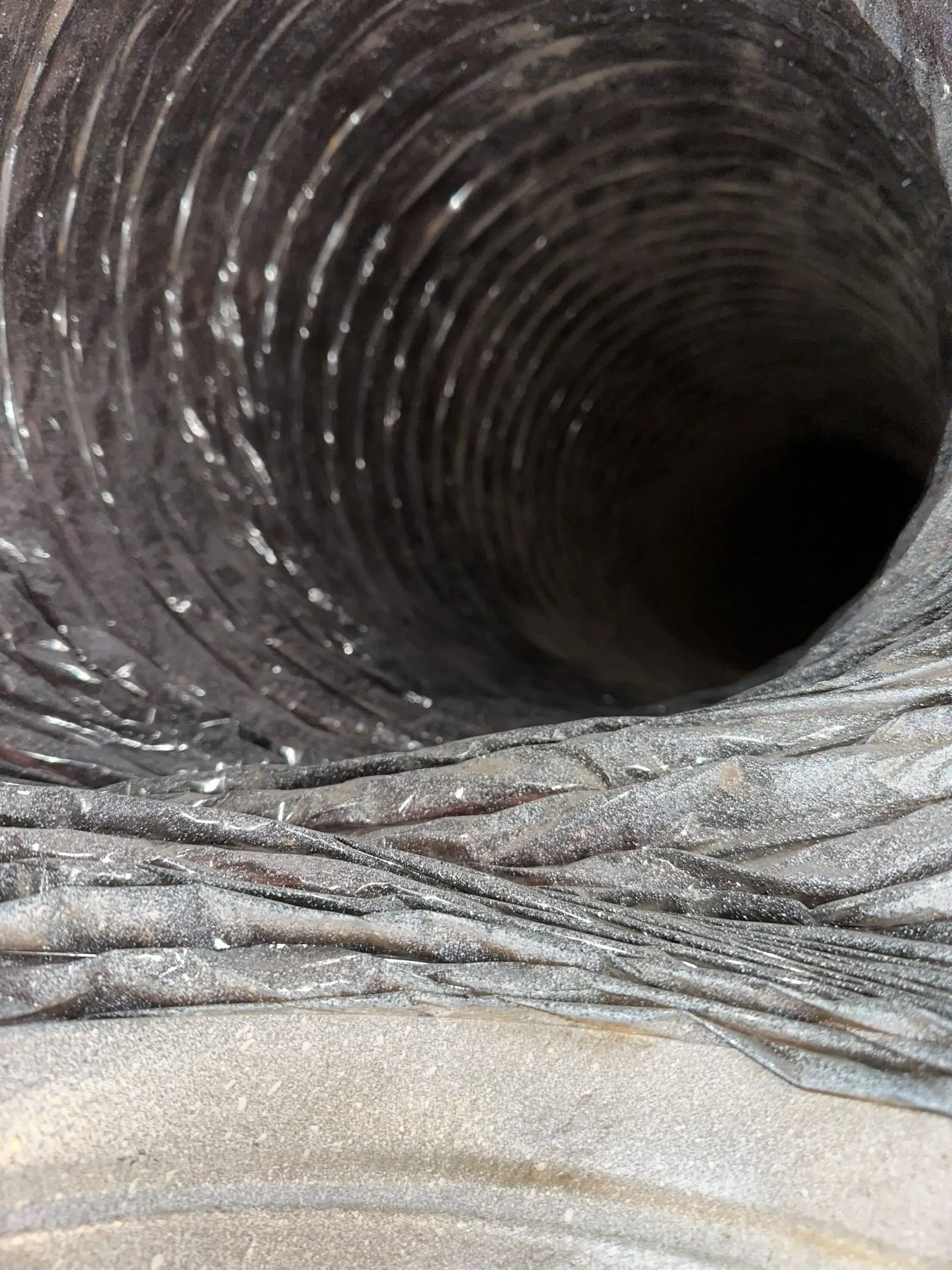 Interior of a flexible air duct run with dust visible along the seams